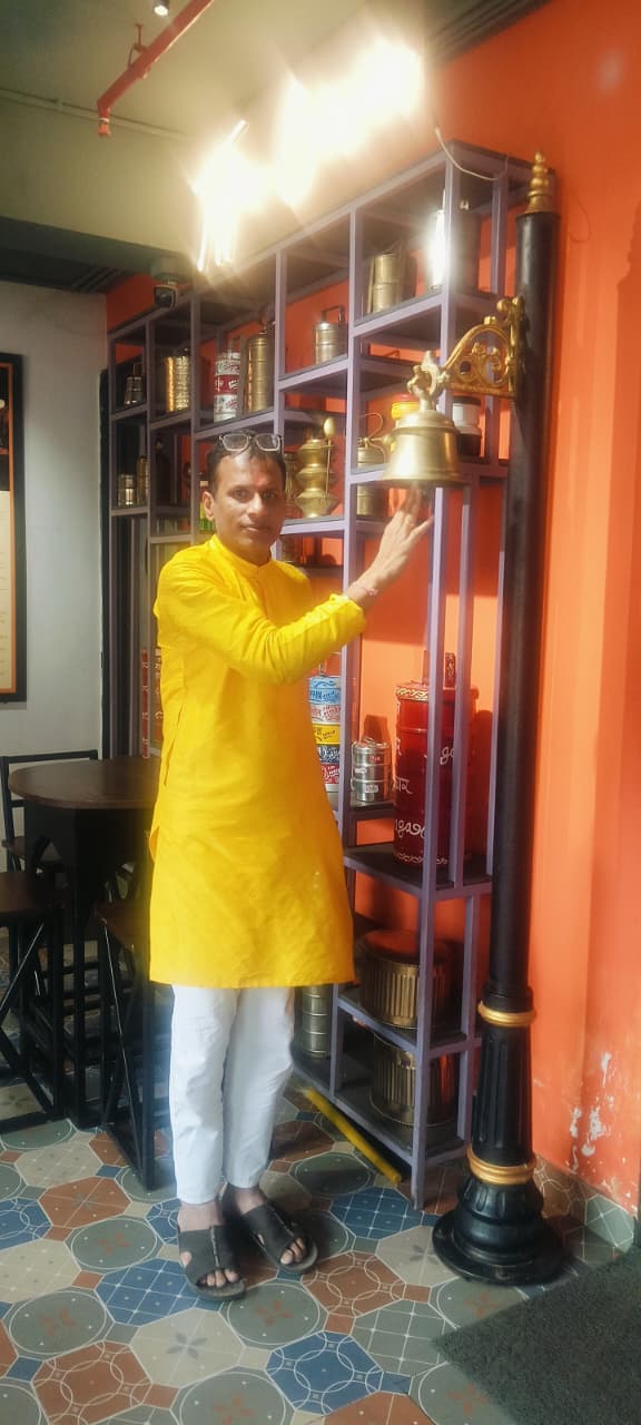 Shri Jay Agarwal ringing a brass bell at a client&rsquo;s caf&eacute;