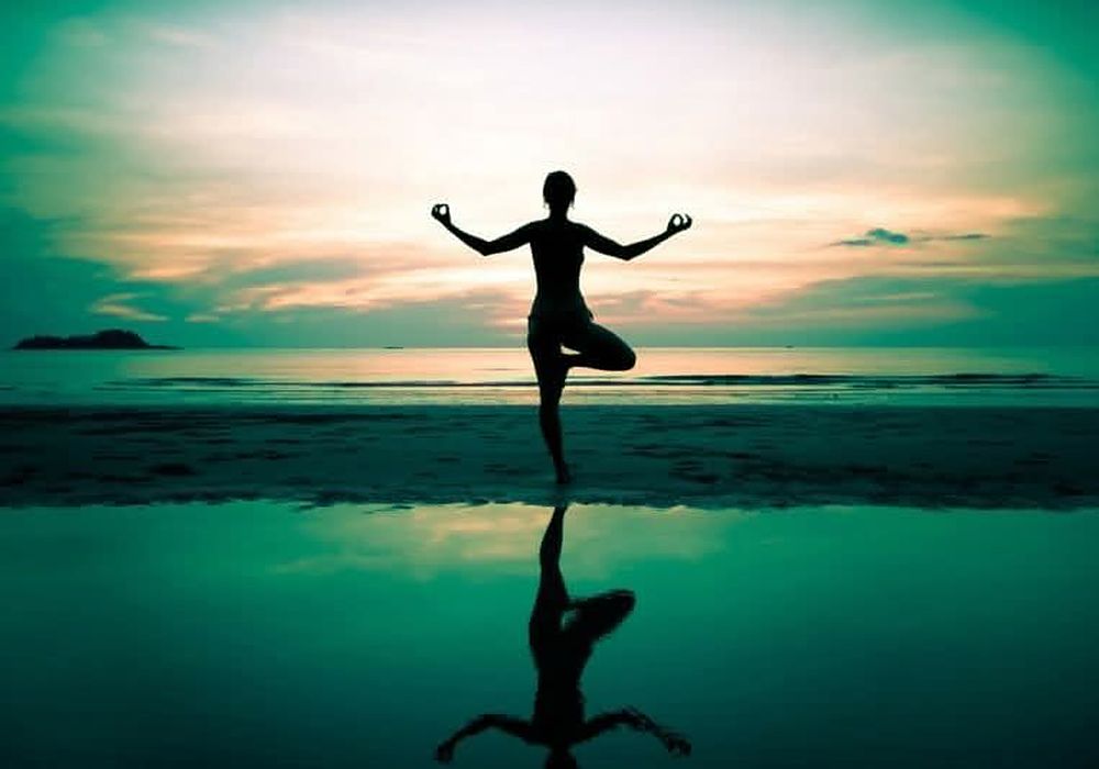 Silhouette of a yoga posture at sunrise over water